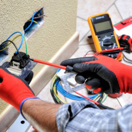 Electrician technician at work blocks the cable between the clamps of a socket in a residential electrical installation